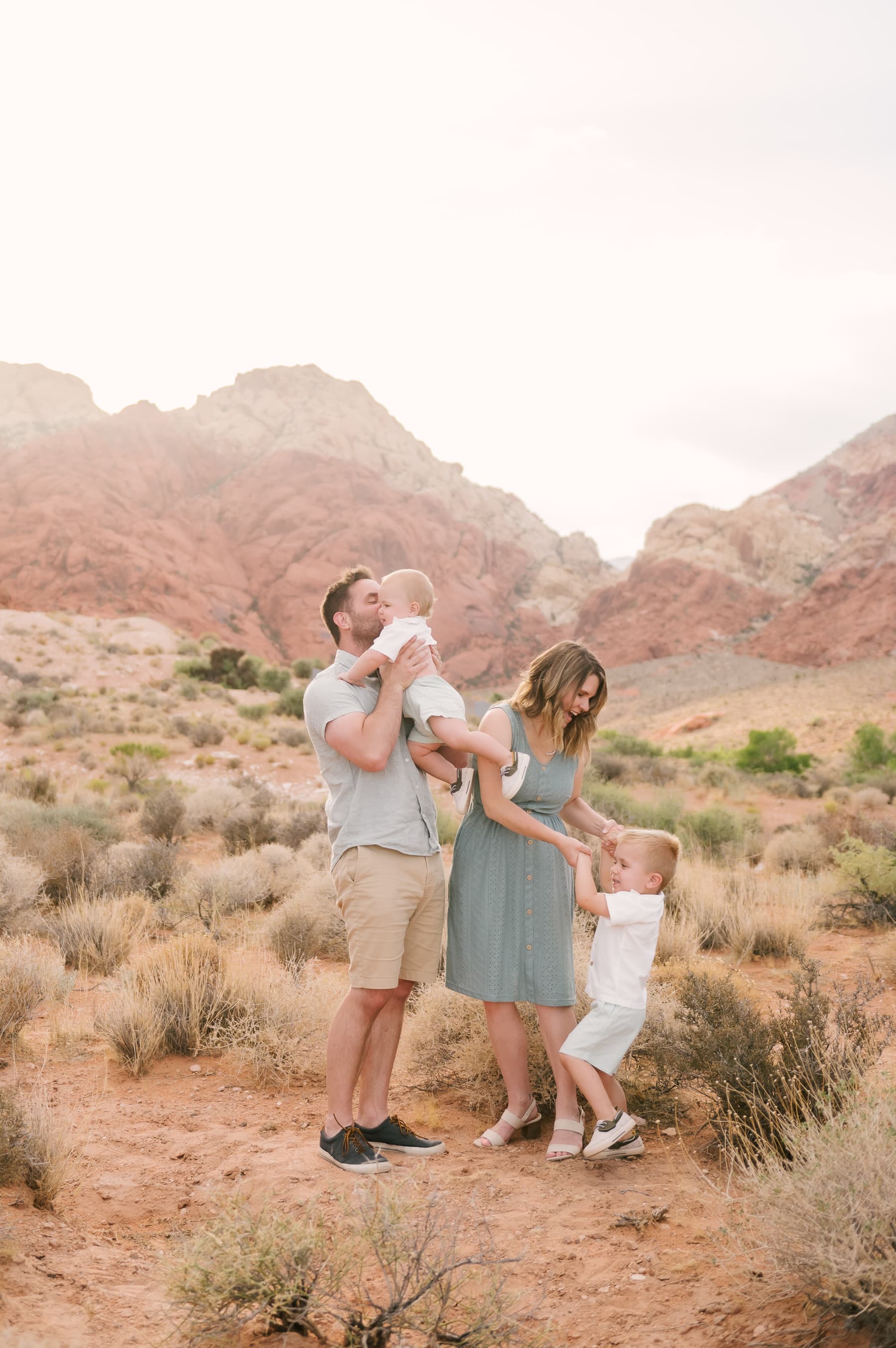 A family of four playing in a desert landscape with scenic red rock mountains behind.